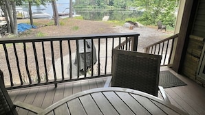 A wooden deck with a view of a lake and forest. - Eva's Place Limit 7 4 Bedroom Home by RedAwning (Sebago)