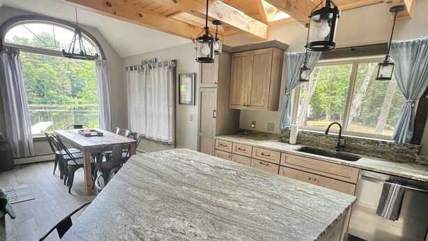 A spacious kitchen with a large island, wooden ceiling beams, and a view of the outdoors. - Eva's Place Limit 7 4 Bedroom Home by RedAwning (Sebago)