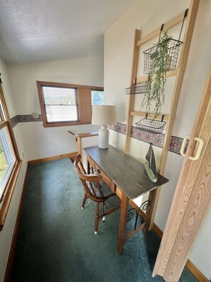 A compact kitchen with a wooden table, chairs, a window, and a hanging plant basket. - Sebago Escape Limit 12 5 Bedroom Home by RedAwning (Raymond)