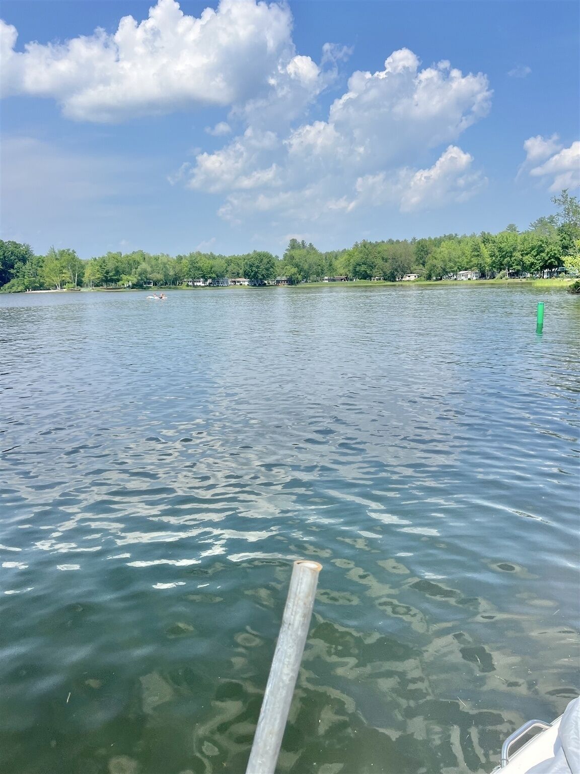 A calm lake with a clear sky and a wooden dock extending into the water.