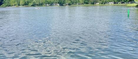 A calm lake with a clear sky and a wooden dock extending into the water.