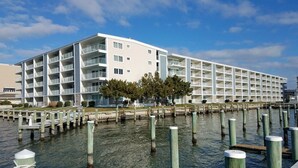 Un hotel sul lungomare con numerosi balconi, un pontile e cielo sereno.