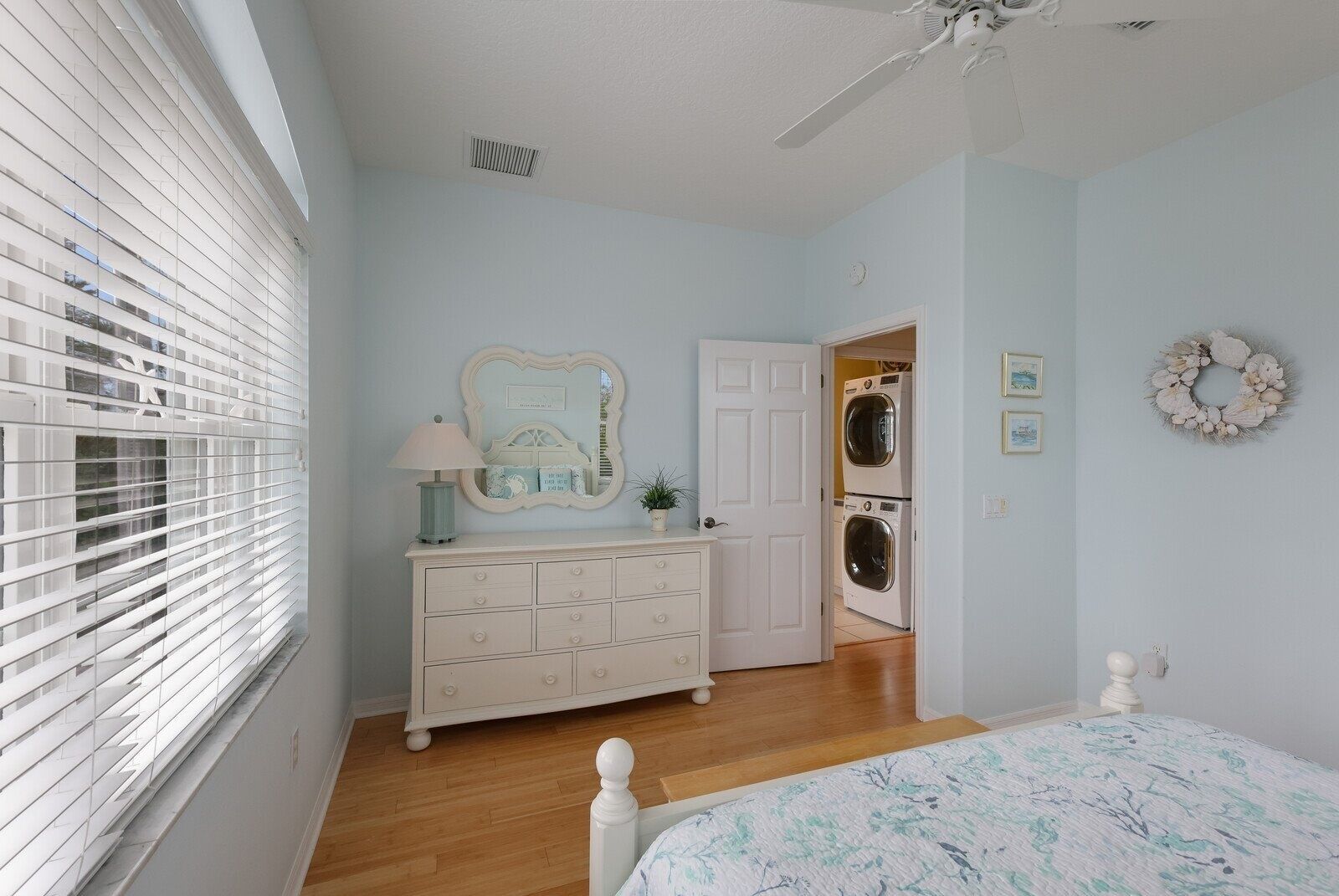 Un dormitorio con cama, cómoda y puerta que da a un cuarto de lavado.