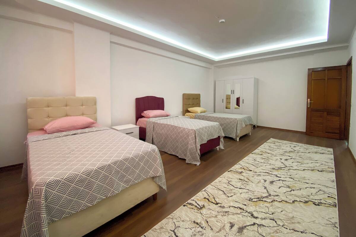 A bedroom with two beds, a wardrobe, and a ceiling light fixture.