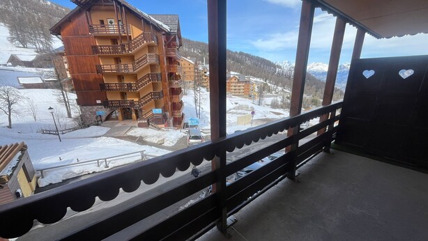 Un balcon donnant sur un bâtiment en bois doté de plusieurs balcons et surplombant un paysage enneigé.