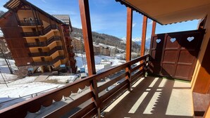 Un balcon donnant sur un paysage enneigé et un bâtiment en bois.