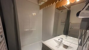 Une salle de bain avec un lavabo blanc, un miroir et une douche.