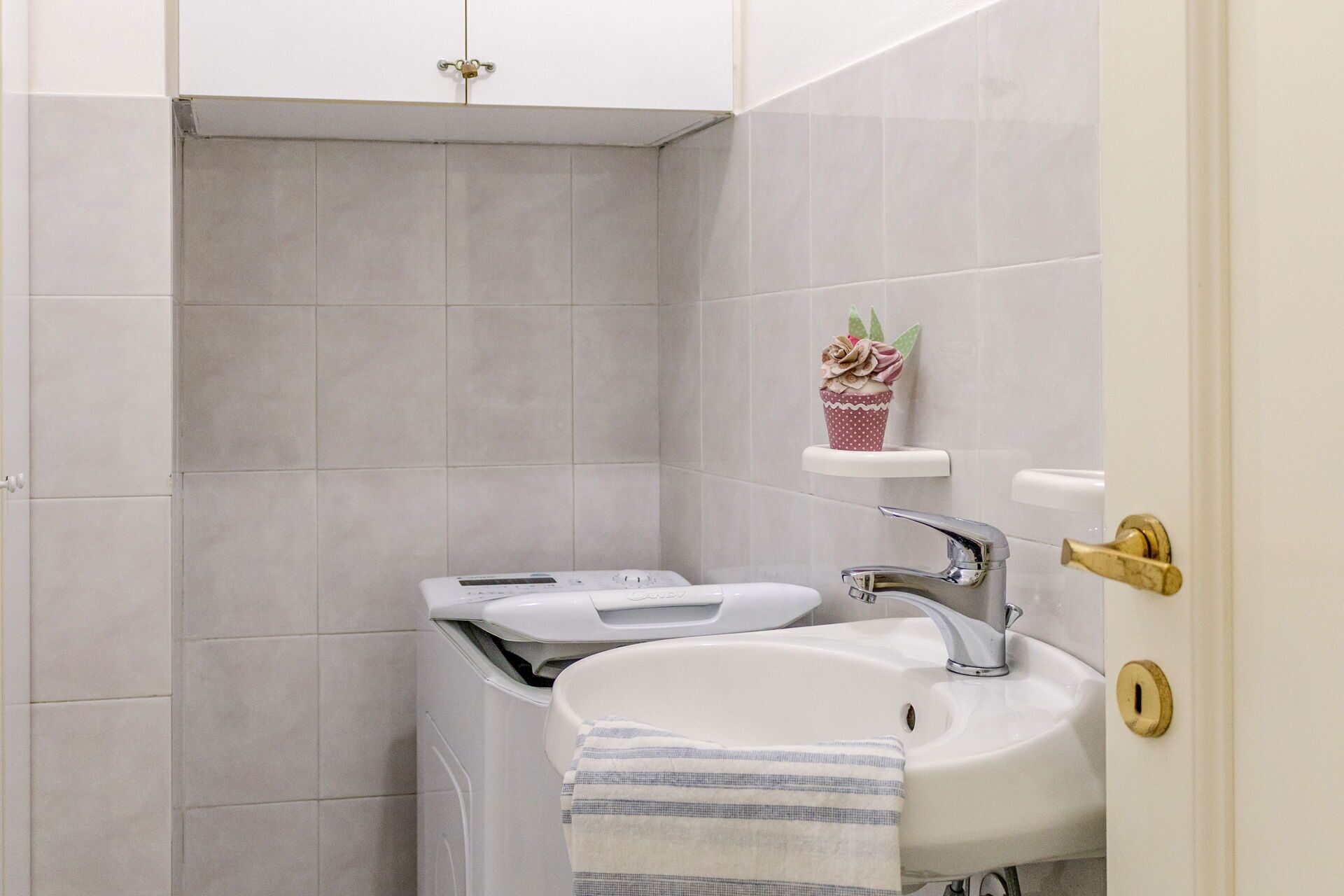 Une salle de bain avec un lavabo blanc, un miroir et des toilettes. Une serviette est accrochée au lavabo.