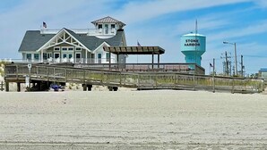 A beach house with a large water tower labeled "Stone Harbor" and a wooden boardwalk leading to the beach. - 6,000 Sq.ft. 18 Guests, 7-Bed, 6-Bath, Pool, Spa, Outdoor Kitchen, Garden, WIFI. (Middle Township)