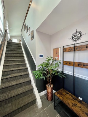 A staircase with a wooden handrail, a potted plant, a wall-mounted coat rack, and a bench. - 6,000 Sq.ft. 18 Guests, 7-Bed, 6-Bath, Pool, Spa, Outdoor Kitchen, Garden, WIFI. (Middle Township)