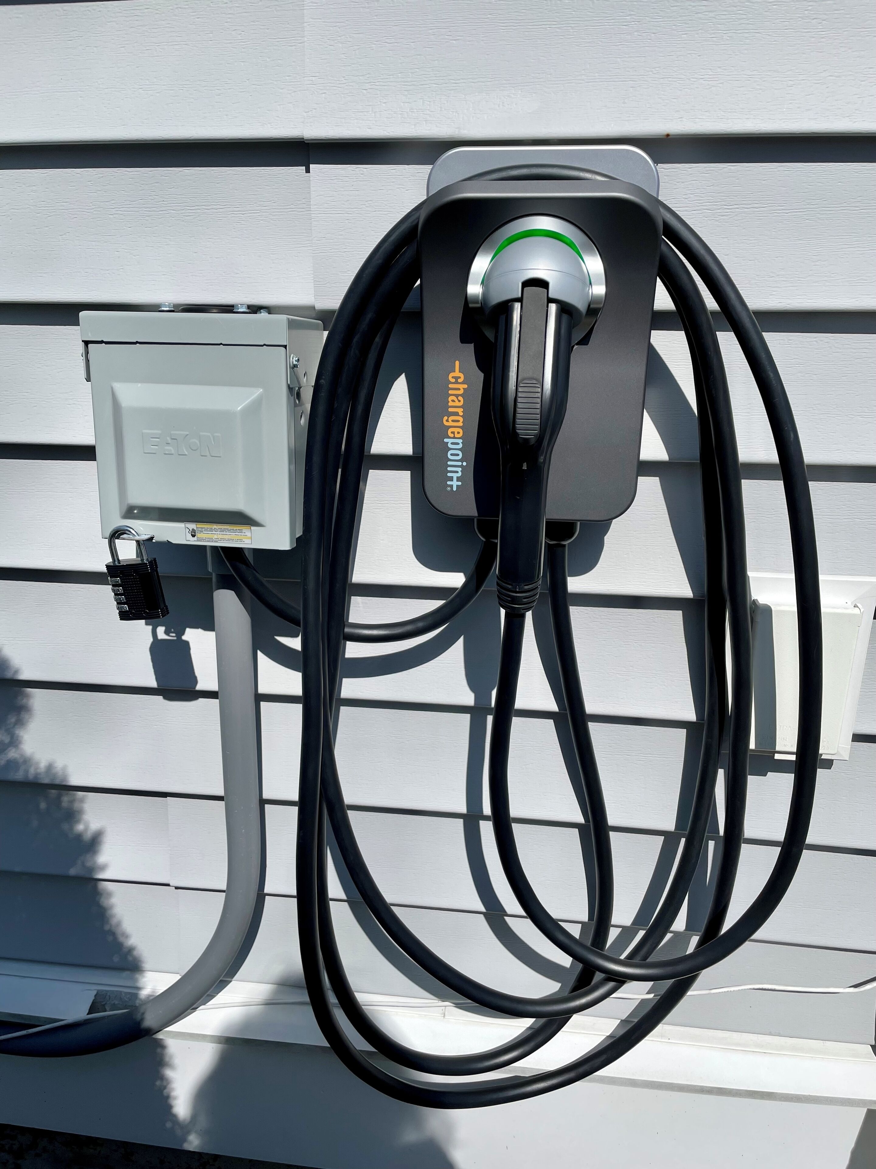 A charging station with a cable connected to a wall-mounted box labeled "EATON" and "charge point".