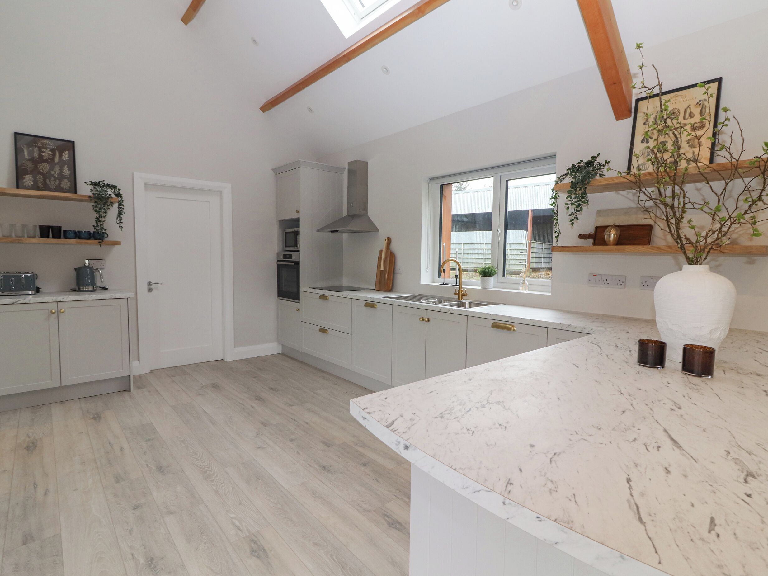 A modern kitchen with white cabinets, a large island, and a window providing natural light.