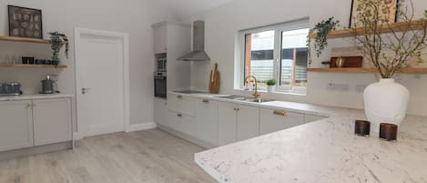 A modern kitchen with white cabinets, a large island, and a window providing natural light.