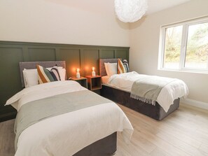 A bedroom with two beds, a large window, and a ceiling light fixture.