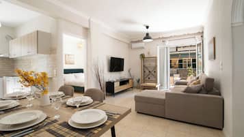 Una sala de estar moderna con comedor, sofá, televisor y vistas al exterior.