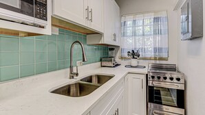 A compact kitchen with a double sink, a built-in oven, and a microwave.