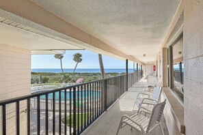Un balcon avec une piscine, des chaises et une vue sur l’océan.