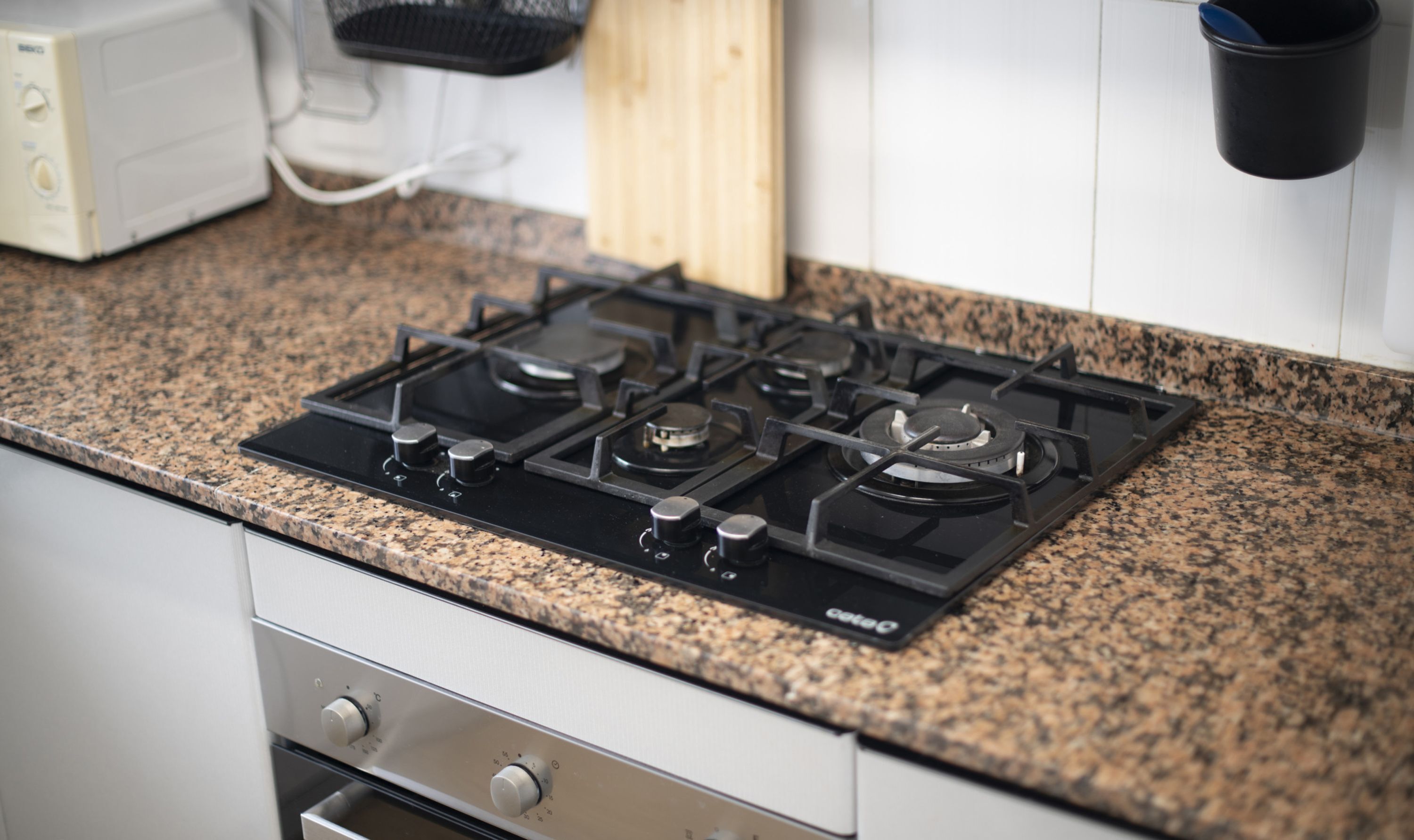 A kitchen with a gas stove, a microwave, and a sink.