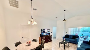 Ein modernes Wohnzimmer mit Essbereich, Fernseher und Sofa.