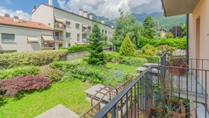 A residential building with a balcony, a garden with various plants, and a mountainous backdrop. - Sunflowers Home - by Varenna Holidays (Mandello del Lario)