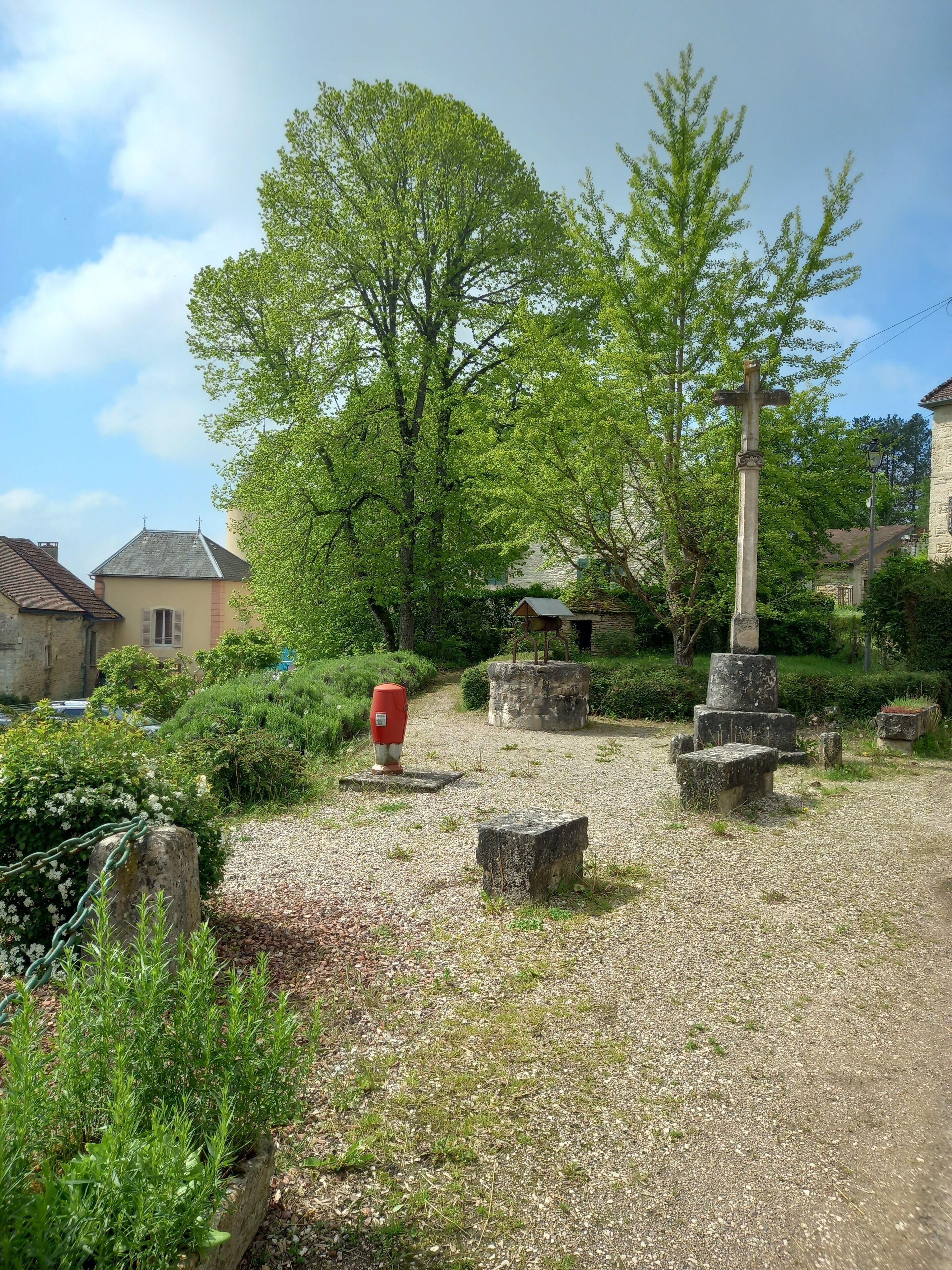 A rural cemetery with stone monuments, a cross, and a gravel path.
