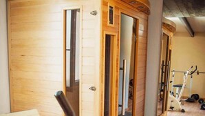 Ein Zimmer mit Holzboden, einer Tür, einem Laufband und Fitnessgeräten.