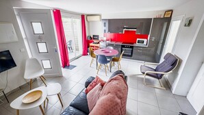 Ein modernes Wohnzimmer mit einer schwarzen Ledersofa, einem weißen Couchtisch und einem Essbereich in Rot und Schwarz.
