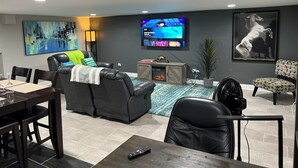 A modern living room with a fireplace, a dining area, and a TV mounted on the wall.