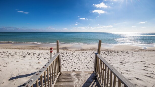 A wooden beach boardwalk leading to the ocean with a clear sky and sun shining. - Surfside Shores By Hosteeva (Gulf Shores)
