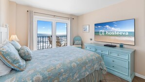 A bedroom with a bed, a dresser, a TV, and a balcony with a view of the sea. - Surfside Shores By Hosteeva (Gulf Shores)