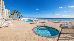 A pool area with lounge chairs and a hot tub, overlooking the ocean. - Surfside Shores By Hosteeva (Gulf Shores)