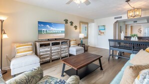 A spacious living room with a flat-screen TV, wooden coffee table, and comfortable seating. - Surfside Shores By Hosteeva (Gulf Shores)