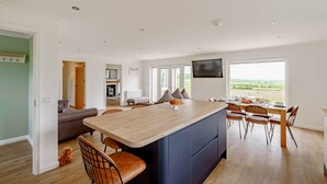A modern kitchen with a central island, dining area, and a view of the outdoors. - Berryrigg Cottage -  a cottage that sleeps 6 guests in 3 bedrooms (Dumfries)