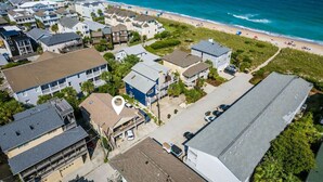 Vista aérea de una zona residencial costera con casas, una playa y un muelle.