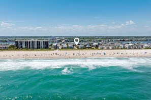 A coastal hotel with a beach view, multiple balconies, and a marina in the background. - Unique Getaway Steps to Wrightsville Beach! (Wrightsville Beach)