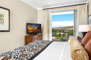 Ein Hotelzimmer mit einem Bett, einem Fernseher, Blick auf eine Landschaft und einem Fenster mit Vorhängen.