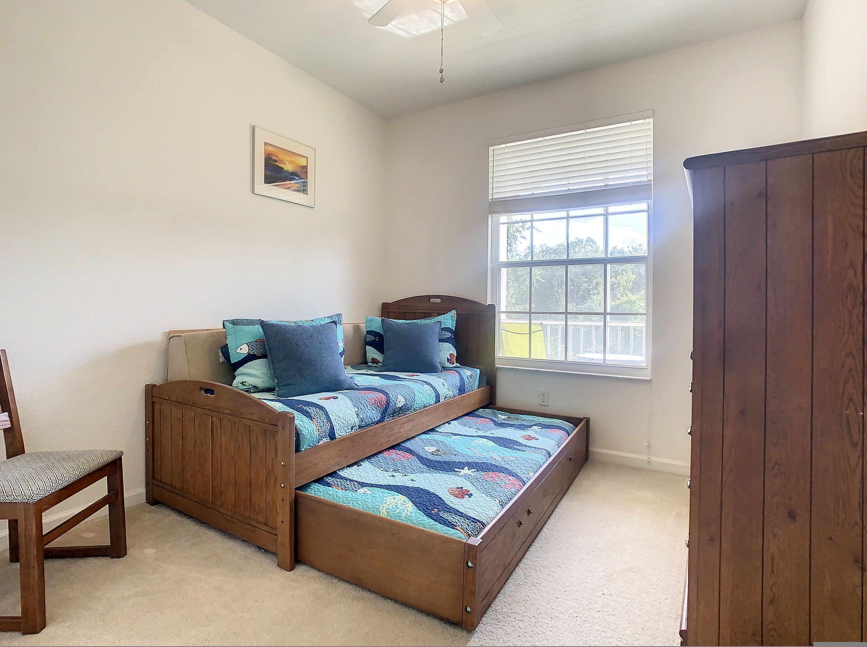 A bedroom with a bed, a chair, a window, and a door.