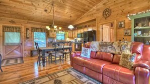 A cozy cabin interior with a dining area, a leather sofa, and a kitchen. - Cozy Cabin near DT Blue Ridge, GA 🌲Mtn Views💧Hot Tub 🔥Fire Pit 🐶P... (Blue Ridge)