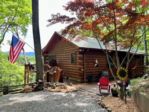 Eine Holzhütte mit Veranda, einer Flagge und einer Sonnenblumen-Dekoration.