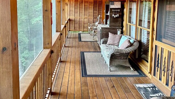A wooden deck with a covered seating area, including a sofa and chairs, and a dining table. - Cozy Cabin near DT Blue Ridge, GA 🌲Mtn Views💧Hot Tub 🔥Fire Pit 🐶P... (Blue Ridge)