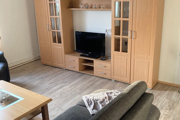 Wohnzimmer mit Couch und Satteliten-TV