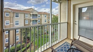 Ein Balkon mit Blick auf ein mehrstöckiges Gebäude, eine Tür mit Fenster und ein kleiner Teppich.