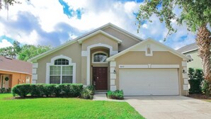A two-story house with a beige facade, a central entrance with an arched doorway, and a garage with the number 8422. - Newly Renovated Home With Calming Atmosphere (Kissimmee)