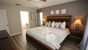 A bedroom with a wooden bed, two bedside tables with lamps, a ceiling fan, and a wooden bench. - Newly Renovated Home With Calming Atmosphere (Kissimmee)