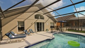 An indoor swimming pool with lounge chairs, a covered patio, and a clear view of the sky. - Newly Renovated Home With Calming Atmosphere (Kissimmee)
