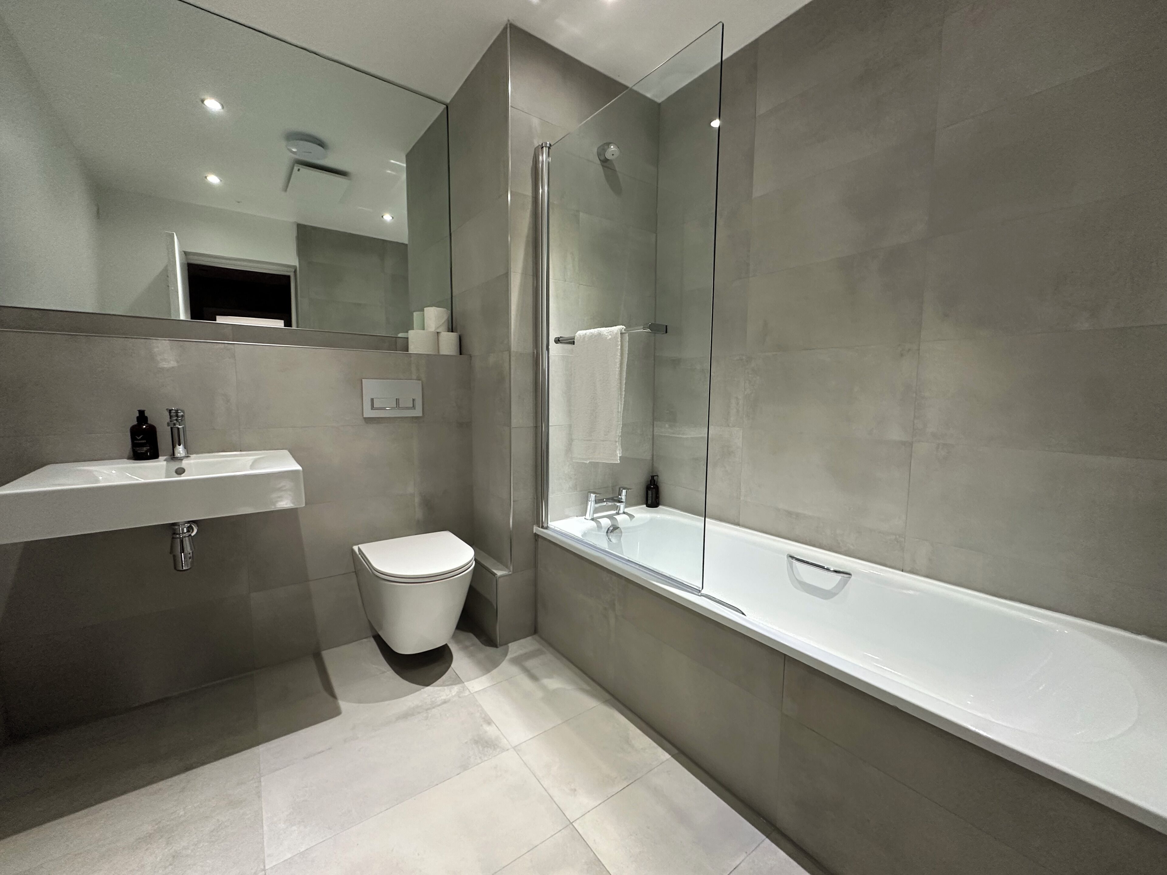 A modern bathroom with a glass shower enclosure, a white sink, and a bathtub.