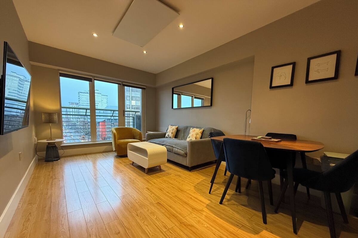 Un salon moderne avec un canapé, un pouf et une table à manger.