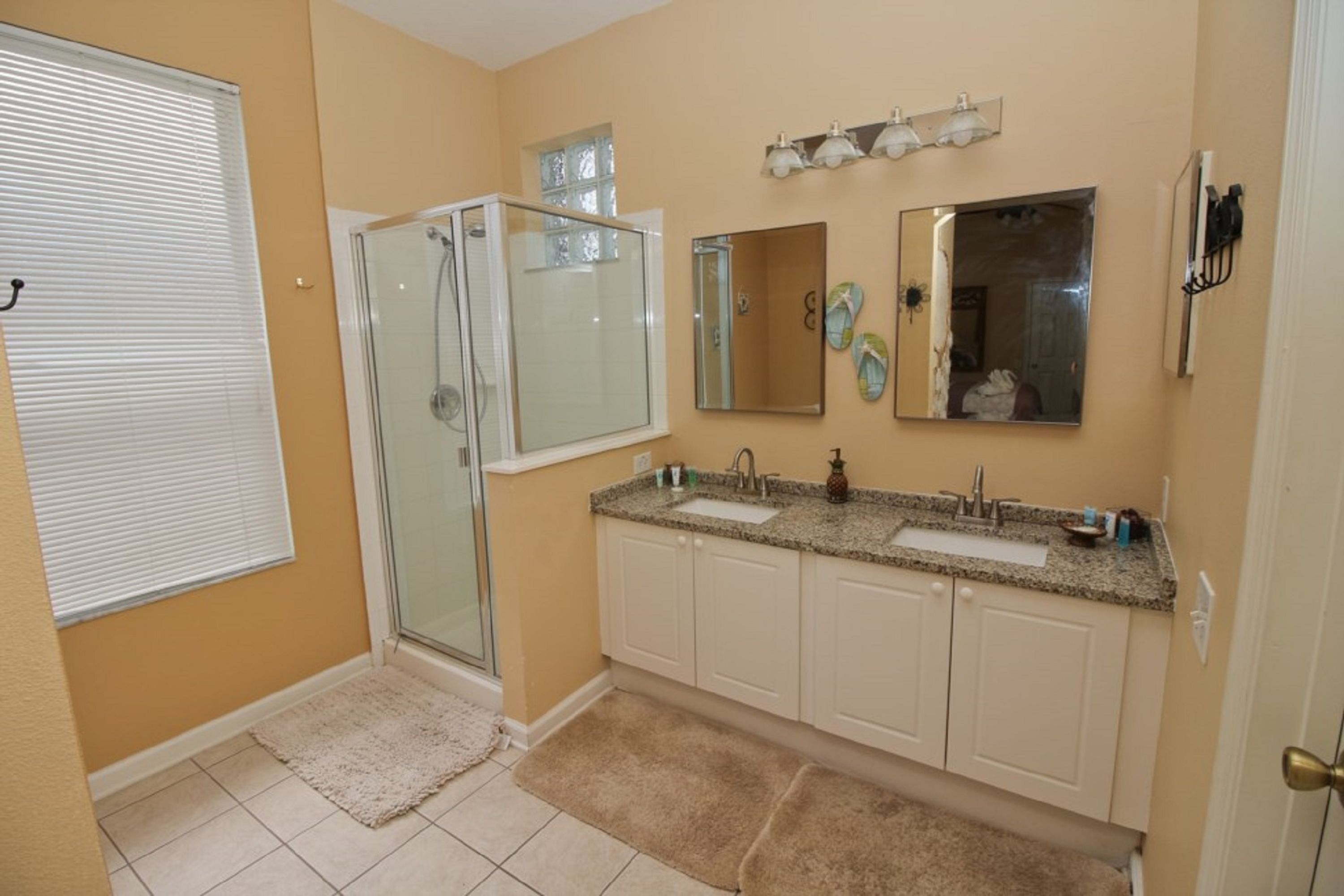 Une salle de bain dotée d’une douche à parois de verre, d’un meuble-lavabo à deux vasques et d’un miroir au-dessus du lavabo.