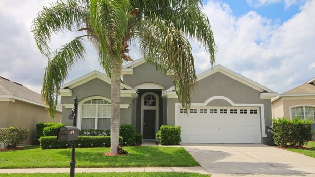 A residential house with a garage, a front yard with a palm tree, and a mailbox.