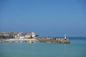 Une ville côtière avec un phare, des bateaux et une plage de sable.